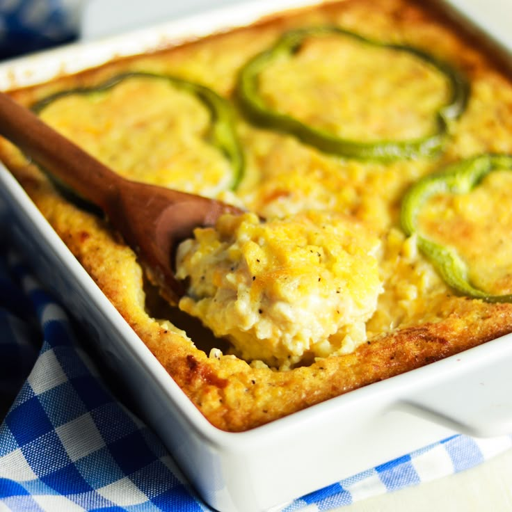 a casserole dish with zucchini and cheese in it on a blue and white checkered table cloth