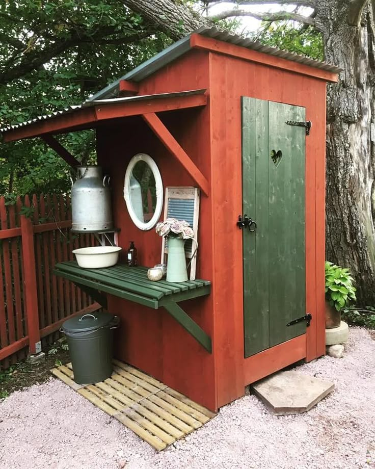 a red shed with a green door next to a tree