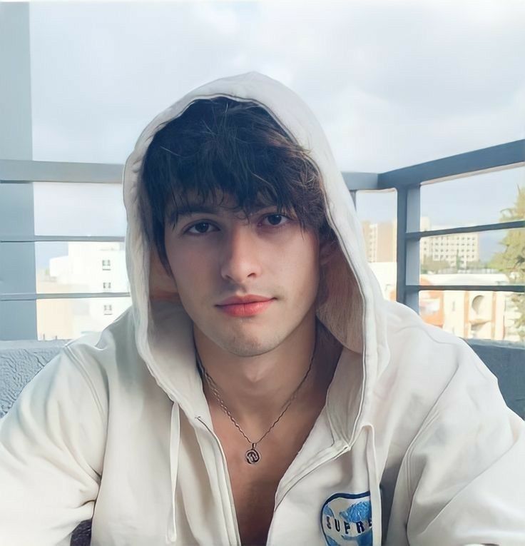 a young man wearing a white hoodie sitting at a table