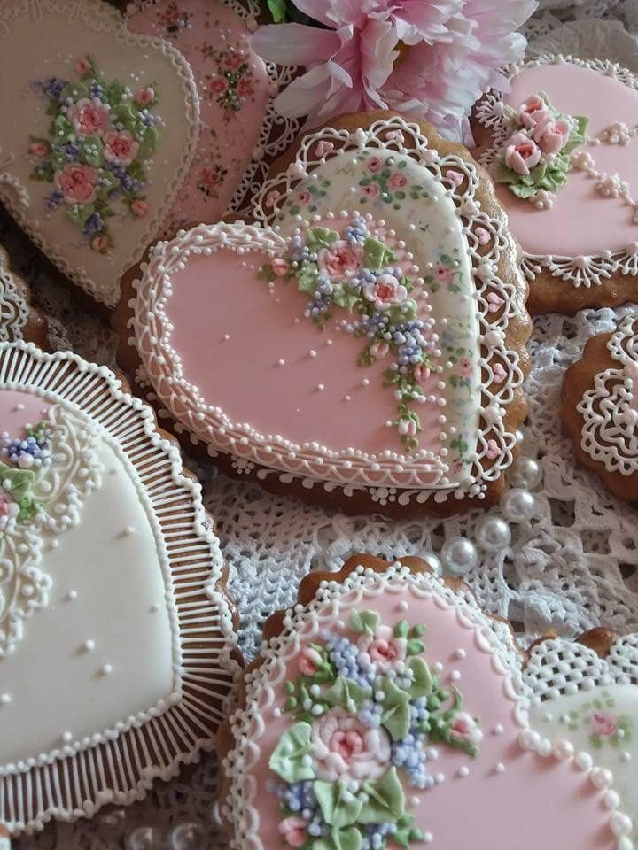 several decorated heart shaped cookies sitting on top of a lace doily covered tablecloth