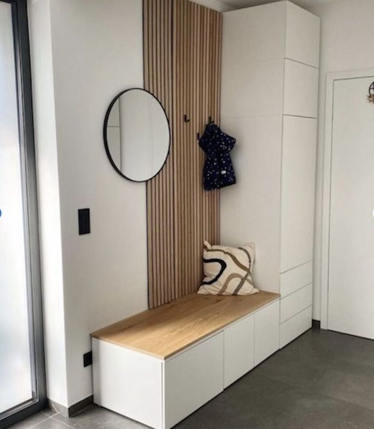 a room with a bench, mirror and coat rack on the wall next to it