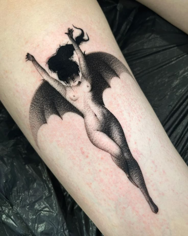 a black and white photo of a woman with a bat tattoo on her leg,