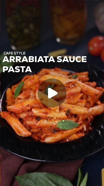 a black plate topped with pasta covered in sauce