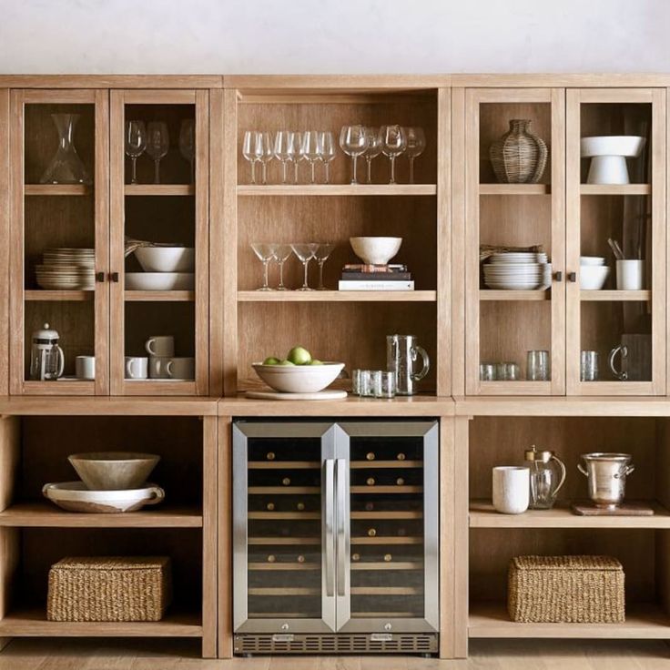 an open cabinet with wine glasses and dishes in it