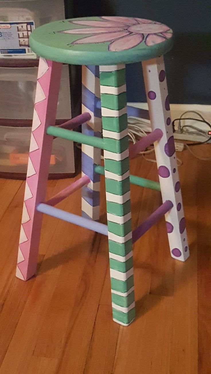 a child's stool made out of wooden sticks and painted in pink, blue, green and white