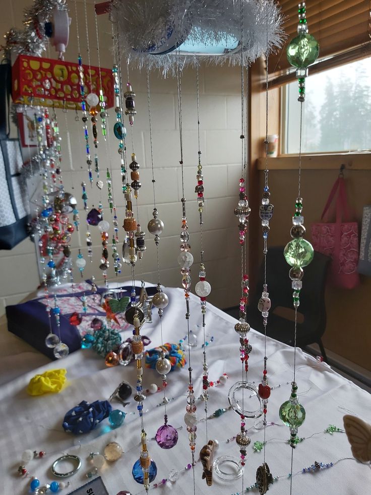 a table topped with lots of different colored glass beads and chains hanging from the ceiling