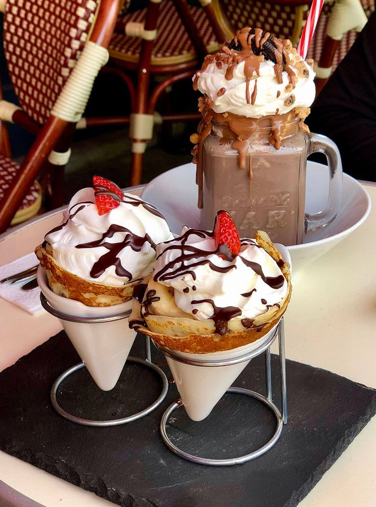 two desserts with whipped cream and strawberries on top are sitting on a table