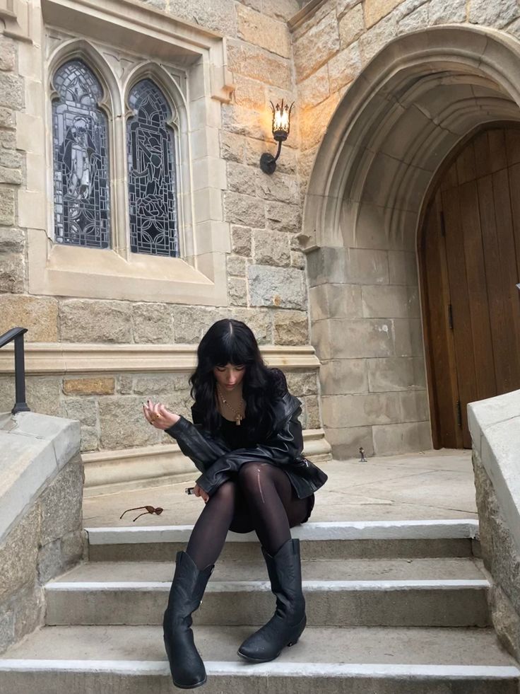 a woman sitting on the steps in front of a building wearing black boots and stockings