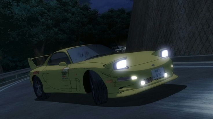 a yellow sports car driving down a street at night