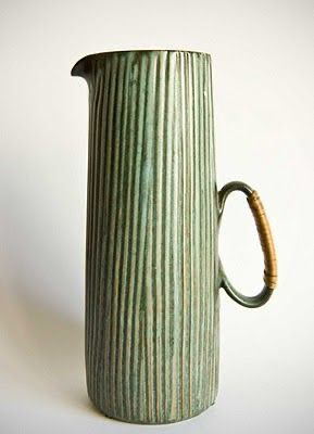 a green vase with a wooden handle on a white background, it appears to be made out of ceramic