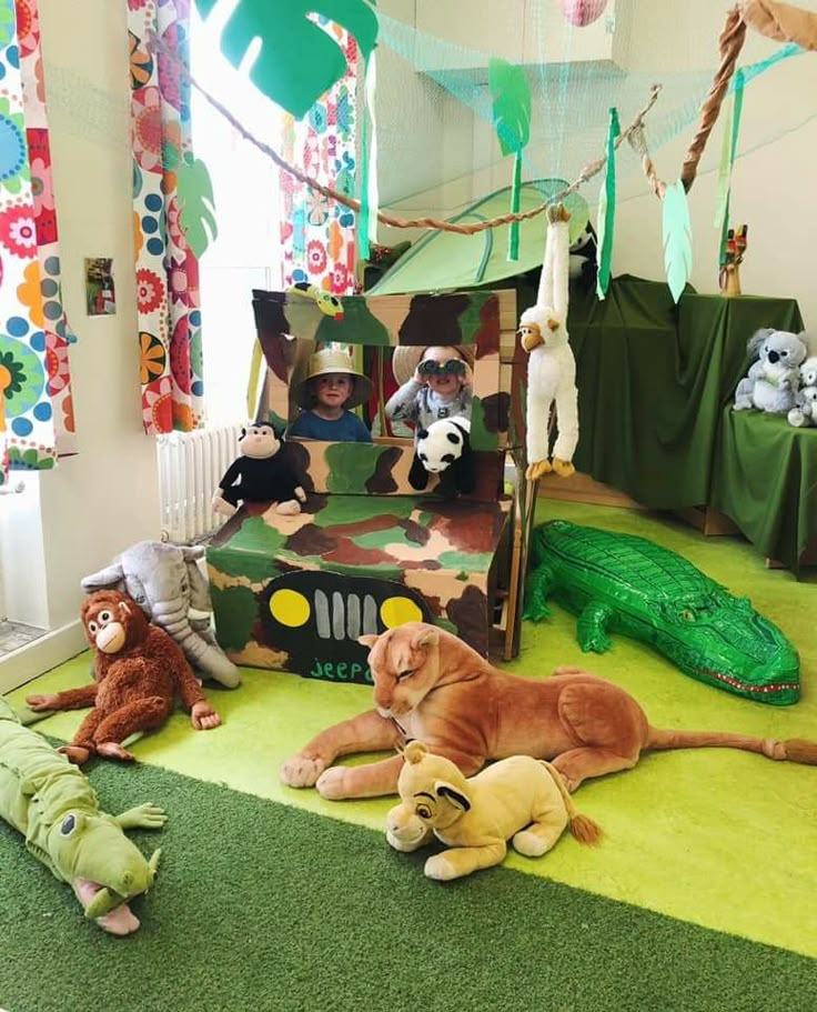 several stuffed animals are sitting on the floor in front of a tent with alligators and giraffes