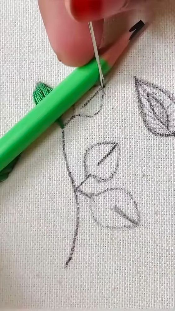 someone is drawing on the fabric with a green pen