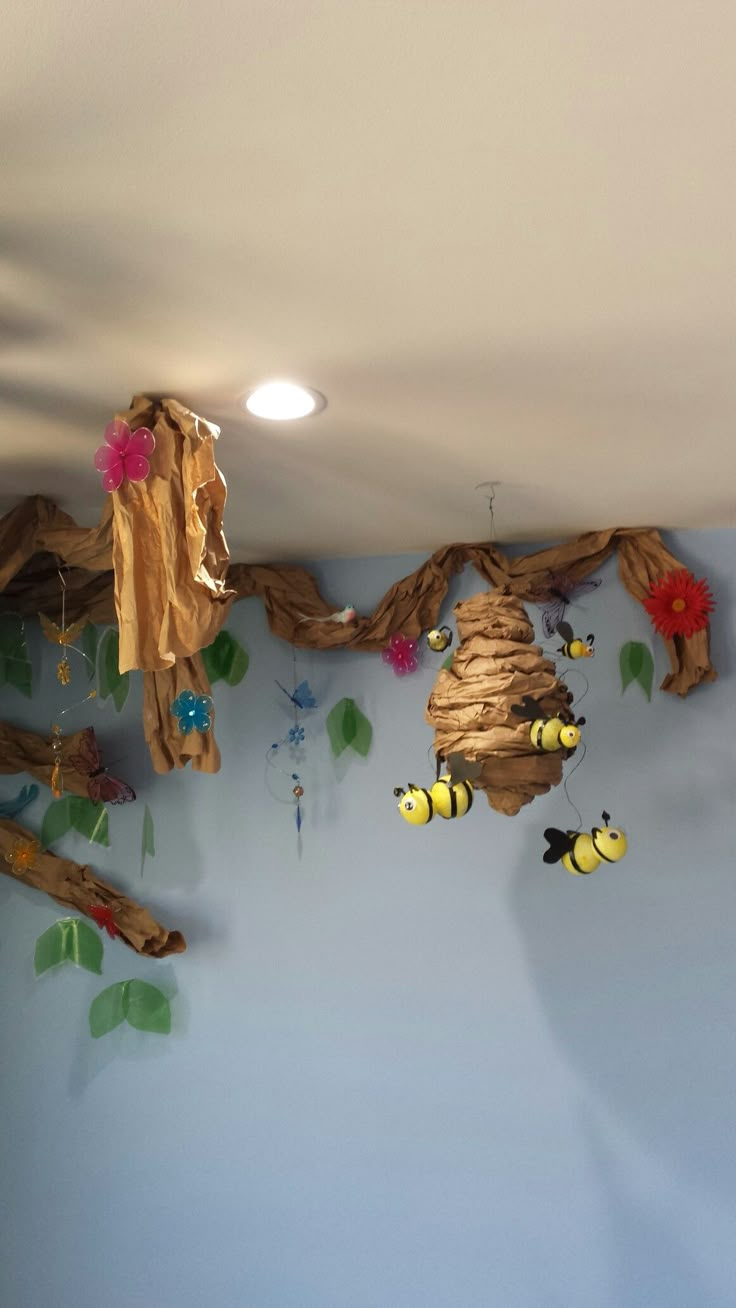 a room with blue walls and decorations on the wall, including bees hanging from branches