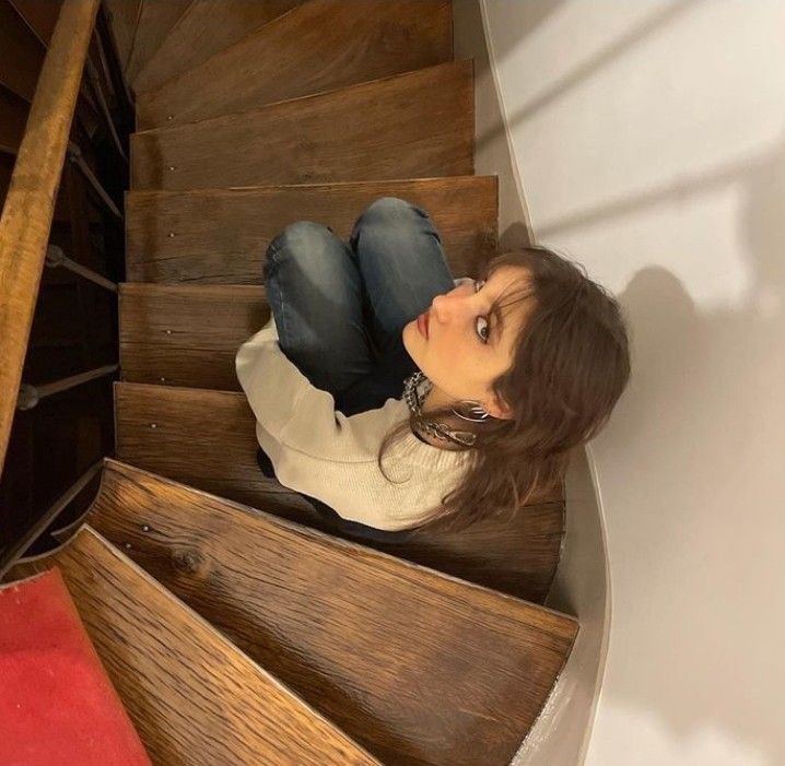 a woman sitting on top of a wooden staircase