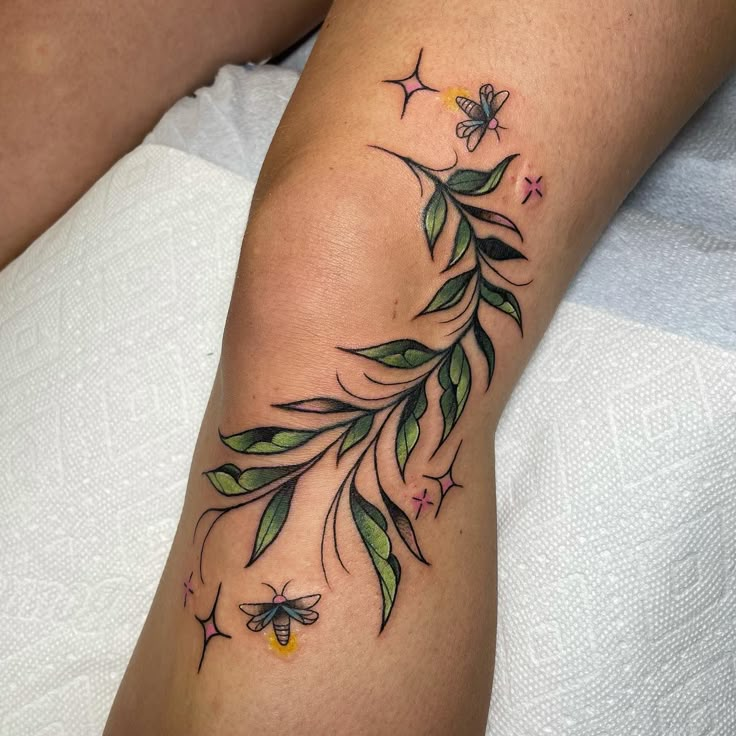 a woman's arm with green leaves and butterflies on it, while the rest of her leg is visible