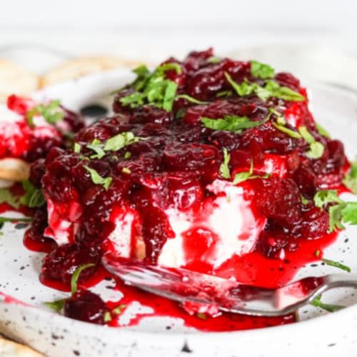 a white plate topped with cranberry sauce and whipped cream next to crackers