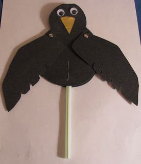 a paper cut out of a black bird on top of a green stick with eyes