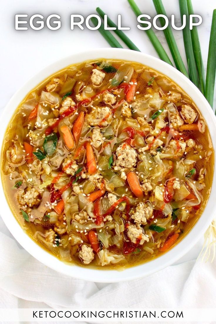 an egg roll soup in a white bowl with green onions and carrots on the side