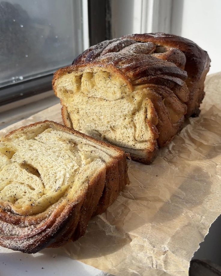 two loaves of bread sitting on top of a piece of paper next to a window