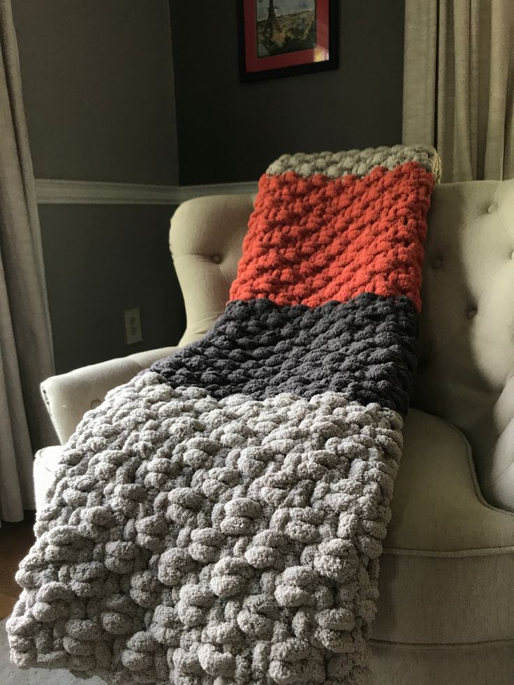 a crocheted blanket sitting on top of a couch next to a white chair