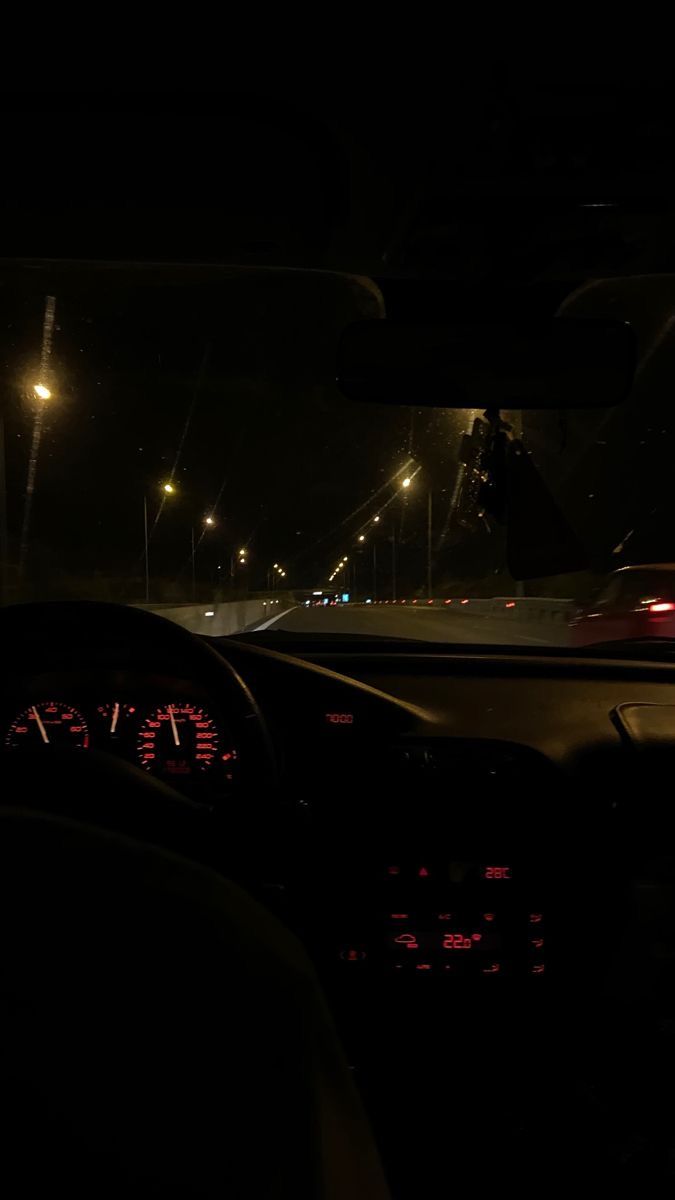 the interior of a car at night with its lights on and dashboard illuminated by streetlights