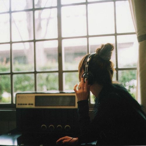 a woman sitting in front of a window talking on a cell phone