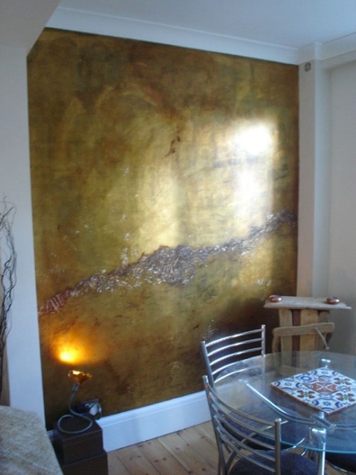 a dining room table and chairs with a painting on the wall behind it that is reflecting sunlight