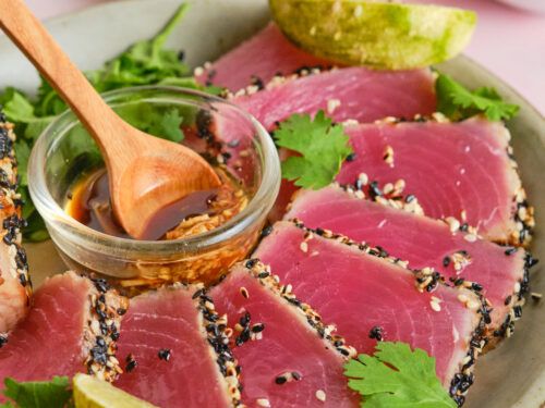 a plate topped with sliced up tuna and garnished with cilantro sauce