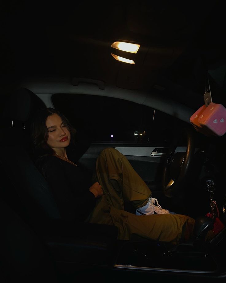 a woman sitting in the back seat of a car at night with her feet up