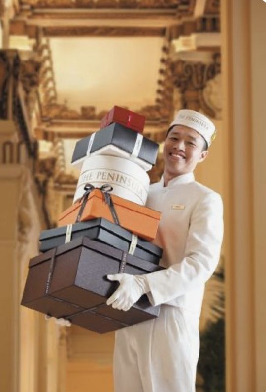 a man in chef's outfit holding a stack of luggage