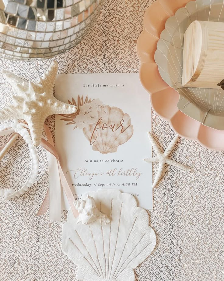 the wedding stationery is laid out with seashells and starfish on the table