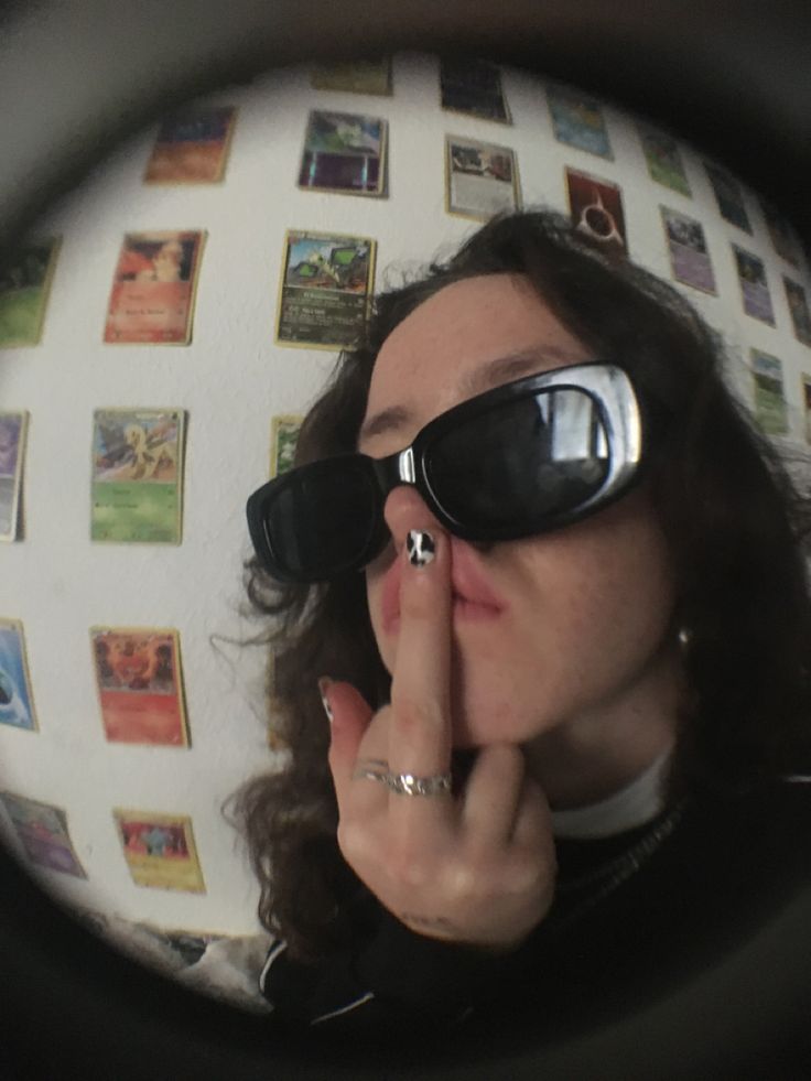 a woman wearing sunglasses is looking through a magnifying glass to see pictures on the wall