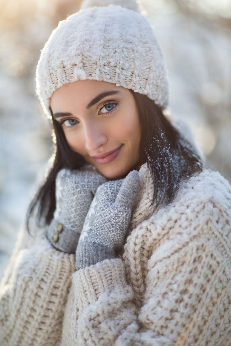 a woman wearing a white hat and mittens posing for a photo in the snow