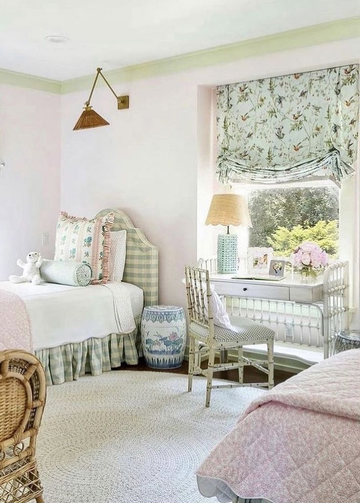 a bedroom with pink walls and white bedding, wicker furniture and window coverings