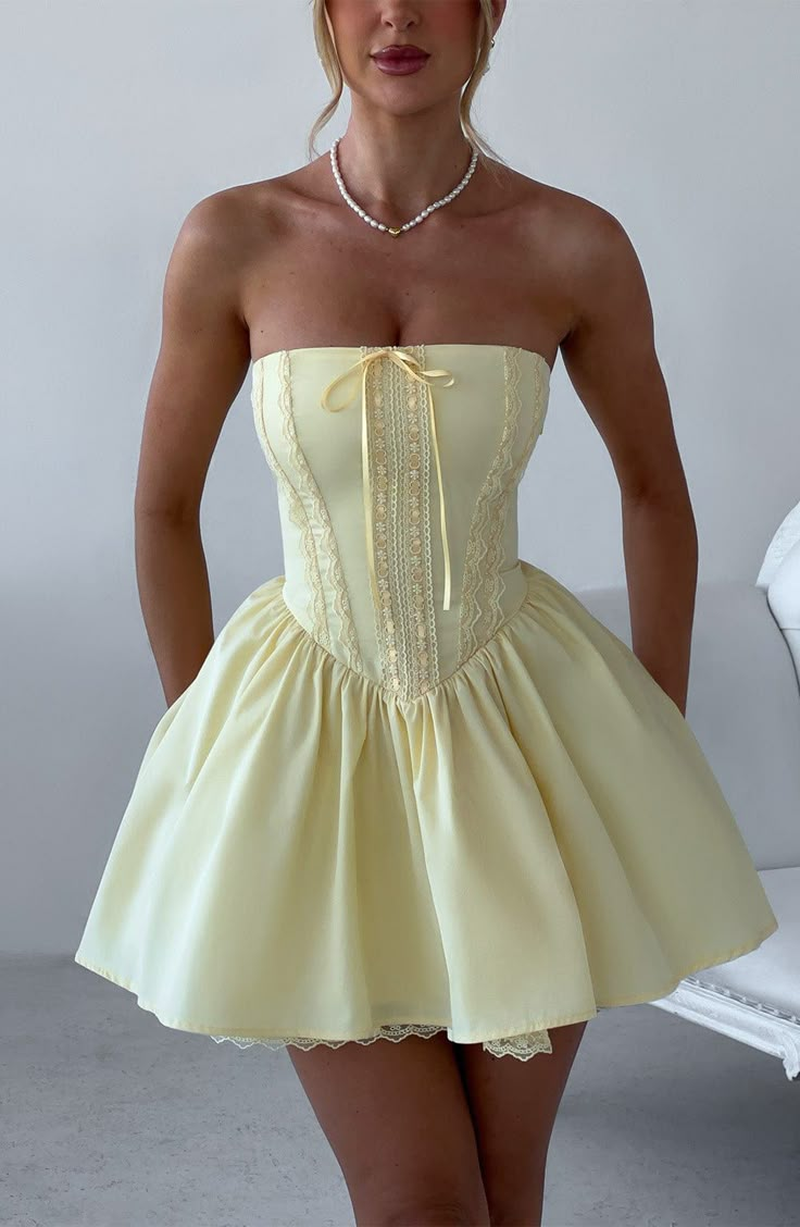 Fall in love with the Evie dress, a flirty mini with a super full skirt made with tulle for extra volume. This strapless style has a boned bodice for an extra snatched look, complete with ribbon to the bust and lace up back. Dress her up with effortless waves, pointed heels and metallic jewellery.    Colour: Lemon.  Non-stretch cotton blend fabric.  Fully lined.  Full skirt with tulle and gathered detail at waist.  Boned bodice with v-shape hem.  Strapless.  Ribbon tie at bust.  Lace trim detail 21 Birthday Outfit Ideas, Short Birthday Dress, 21st Birthday Dress, Homecoming Dresses Satin, Vestidos Color Vino, Strapless Homecoming Dresses, Lace Up Back Dress, Dinner Dresses, Dresses Satin