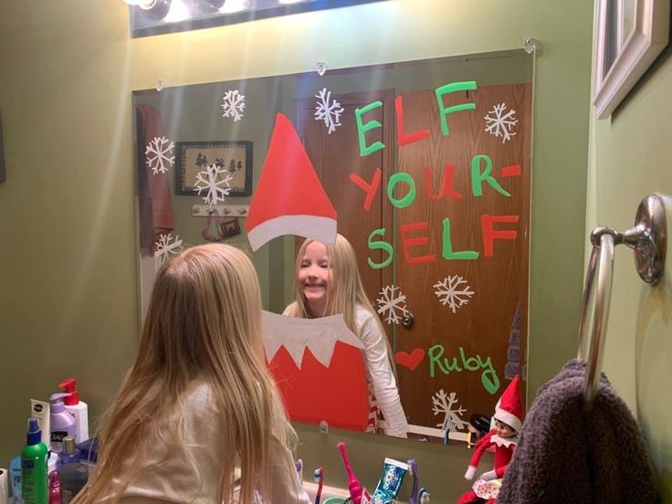 two girls are in the bathroom with elf signs on the wall