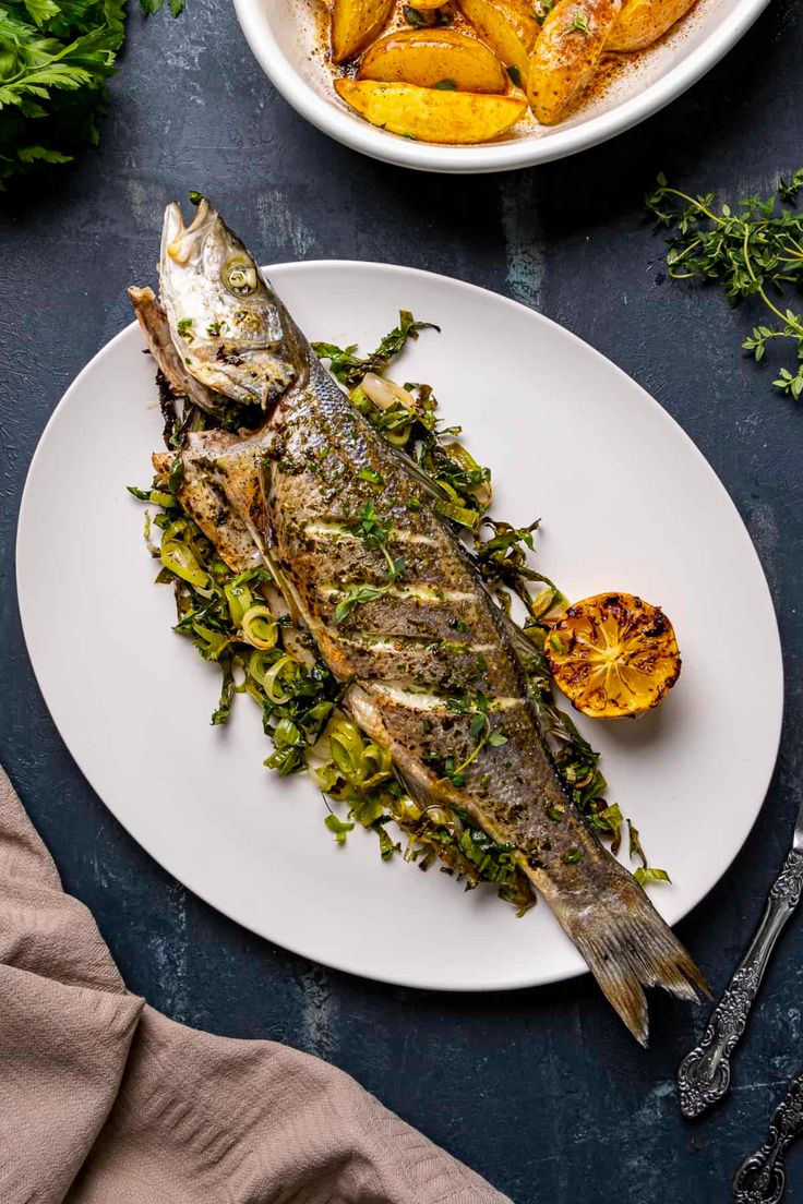 a fish is on a white plate next to some vegetables