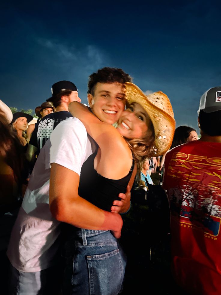 a man and woman hugging each other in front of an audience at a music festival