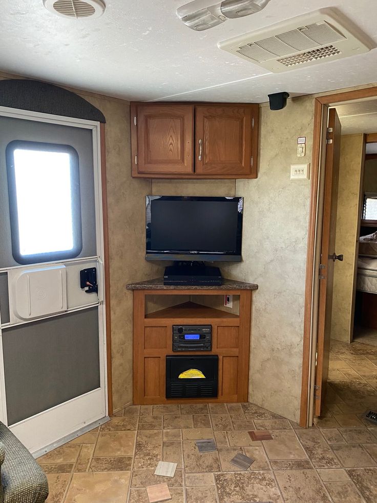 the inside of a travel trailer with an entertainment center and tv in it's corner