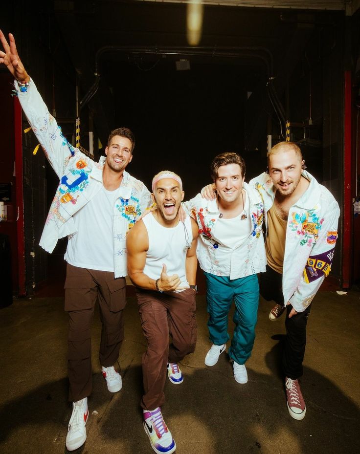 three men in white shirts and brown pants posing for the camera with their arms around each other