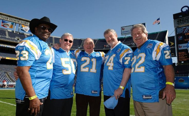 four men in blue jerseys posing for a photo at a football game on the field