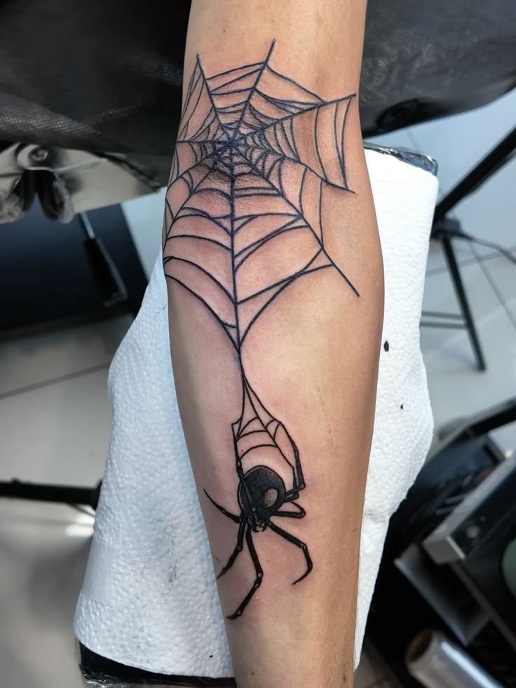 a spider web tattoo on the arm