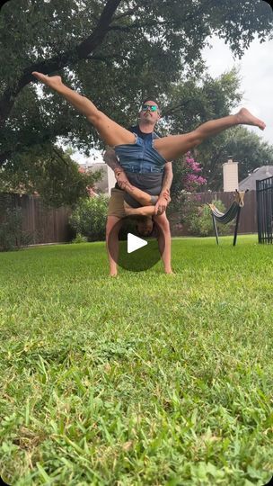 a man doing a handstand in the grass with another man standing behind him