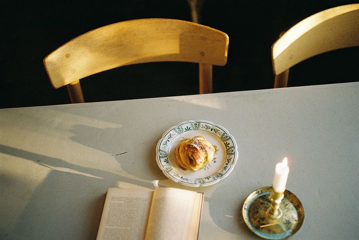 an open book sitting on top of a white table next to a plate with food