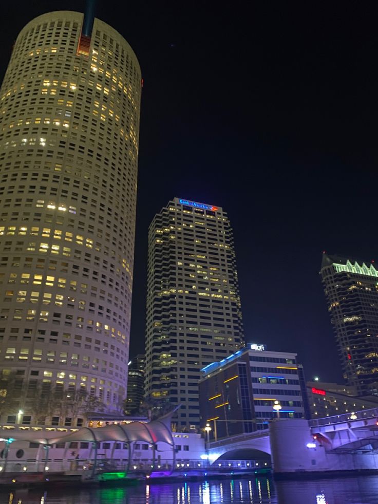 some very tall buildings by the water at night