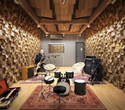 two men are playing drums in a room with wood paneling on the walls and floor