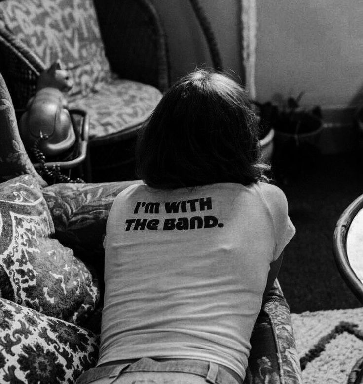 a woman sitting on top of a couch with her back to the camera while wearing a t - shirt that says i'm with the band