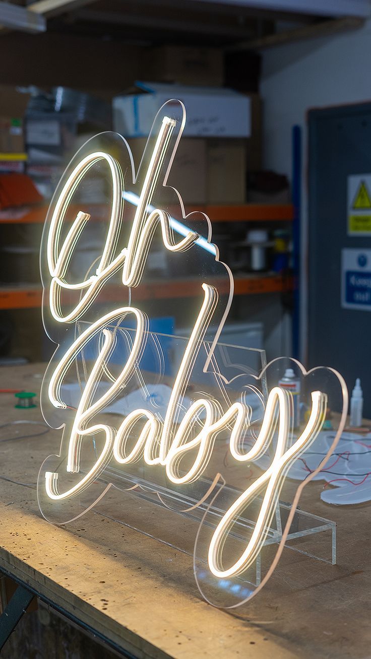 a neon sign that says oh baby on top of a wooden table in a shop