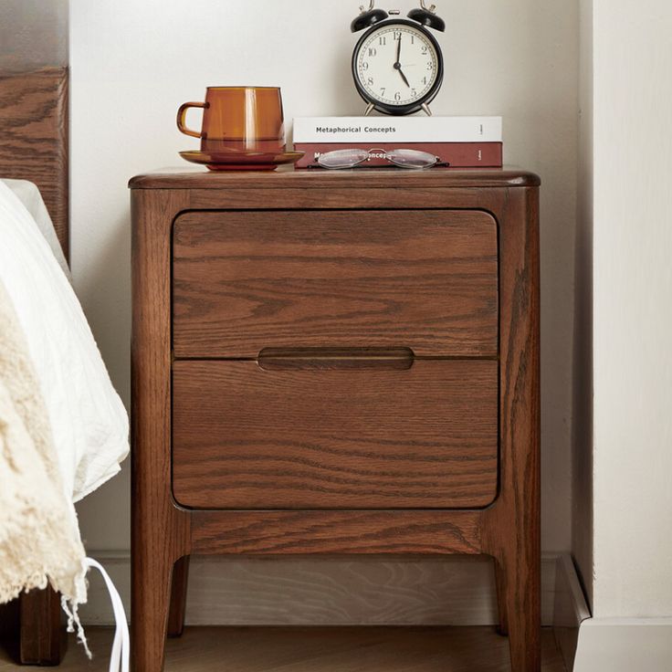 a nightstand with a coffee cup and alarm clock on it