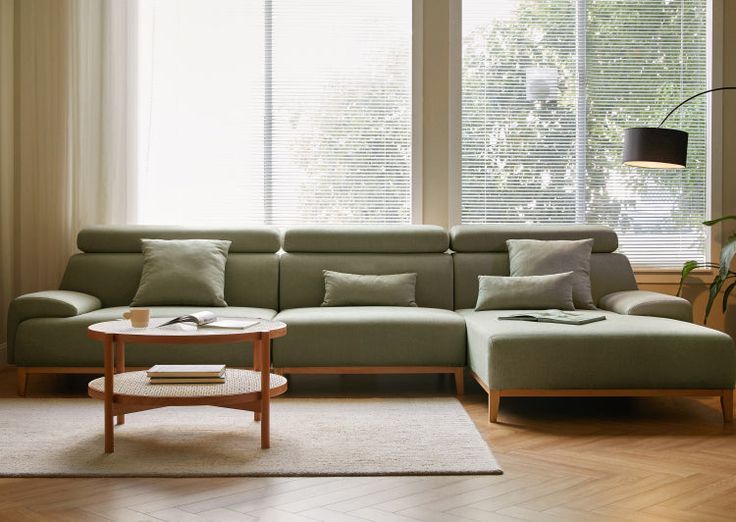 a living room filled with furniture and a large window covered in shades of green curtains